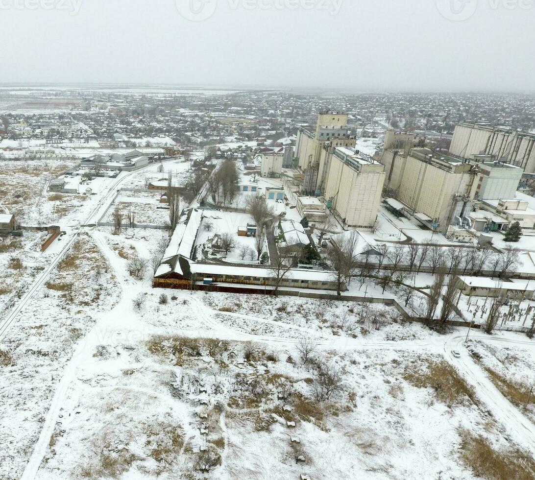 Sprinkled with snow grain elevator. Winter view of the old Soviet elevator. Winter view from the bird's eye view of the village. The streets are covered with snow photo