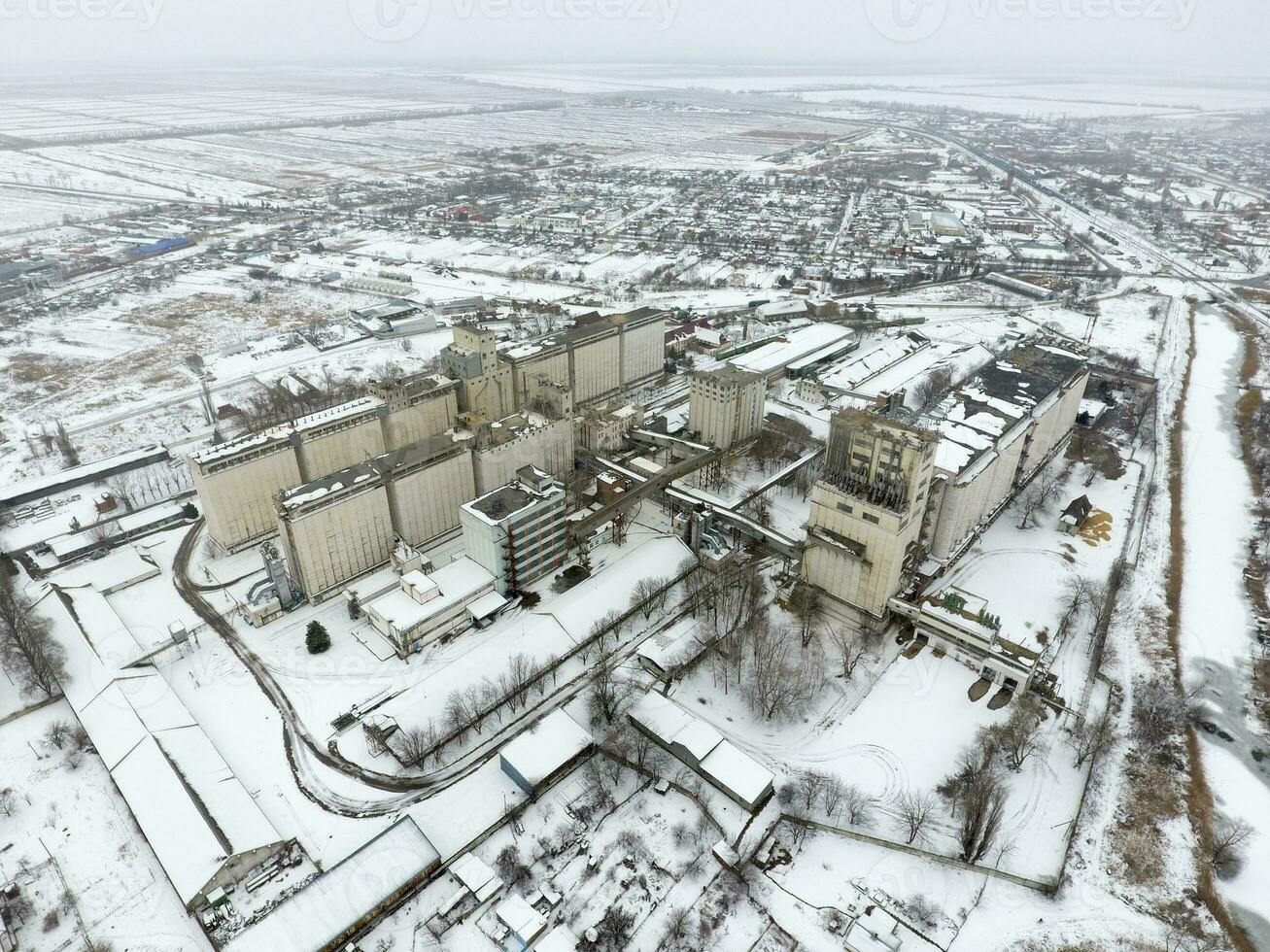 Sprinkled with snow grain elevator. Winter view of the old Soviet elevator. Winter view from the bird's eye view of the village. The streets are covered with snow photo