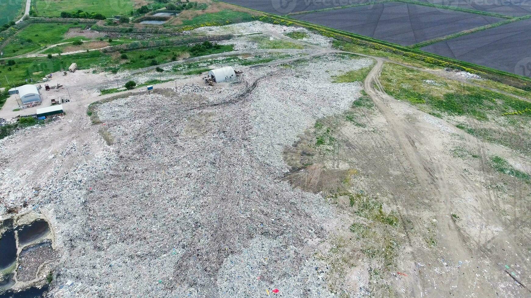 garbage dump with heaps of garbage and treatment facilities. Landfill of garbage outside the village photo