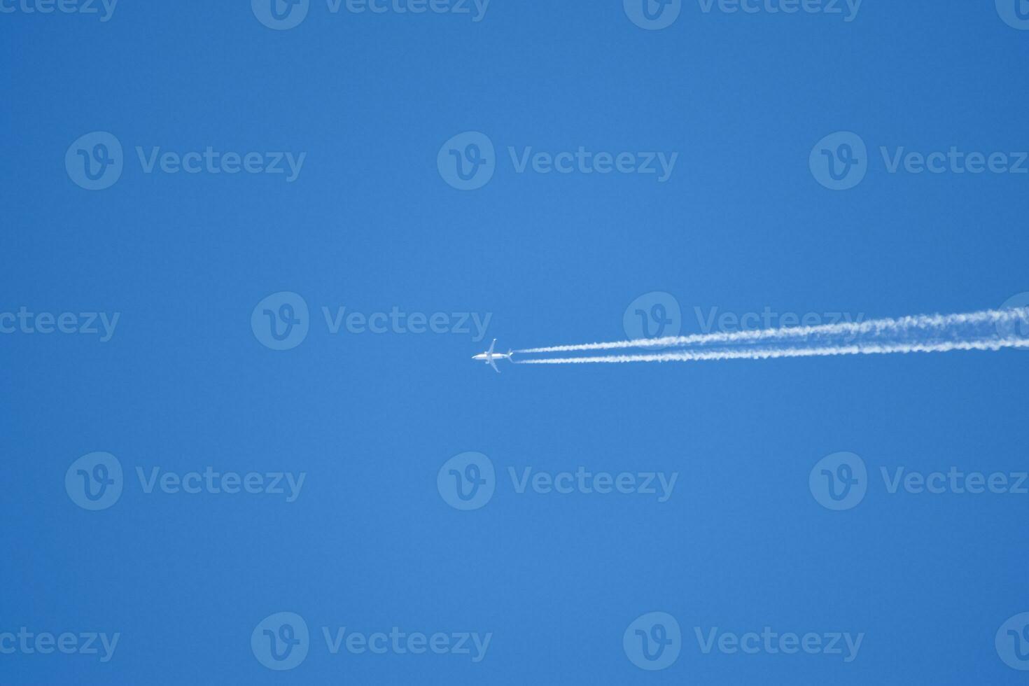 Condensation trail from an airplane in a blue sky photo