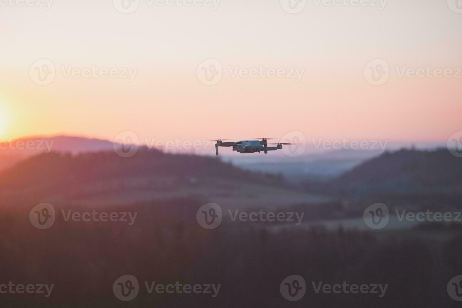 Mobile drone at work during sunset. Technological innovation in photography and aviation. Aerial view video recording. Flying device photo