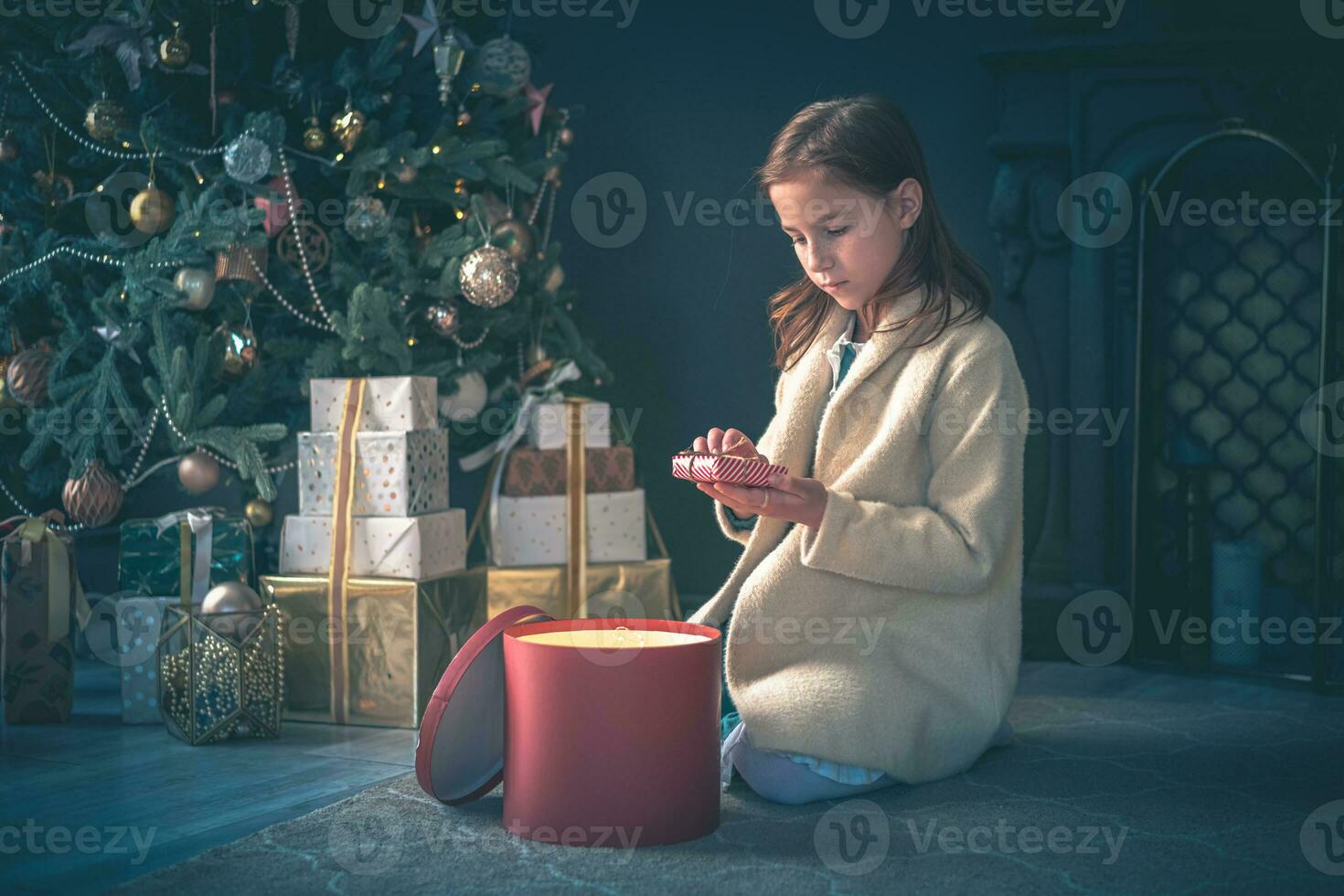 Cute girl opening Present next to Cristmas Tree. photo