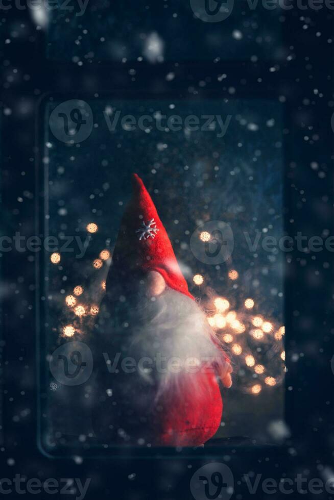 Christmas, winter composition. Christmas Gnome behind a frozen window photo