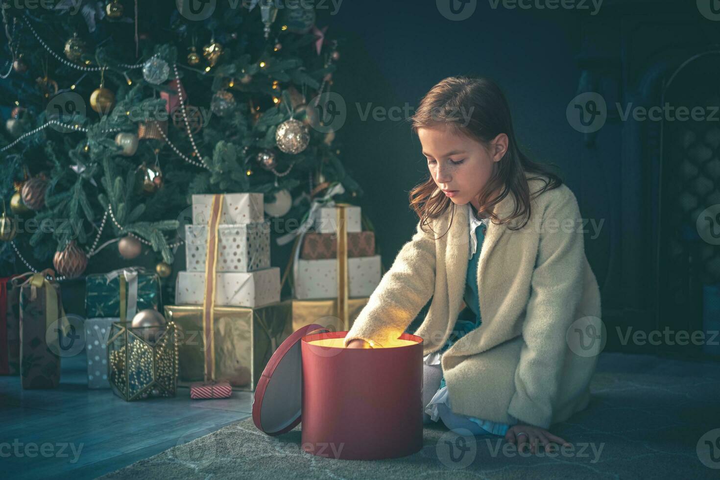 Cute girl opening Present next to Cristmas Tree. photo