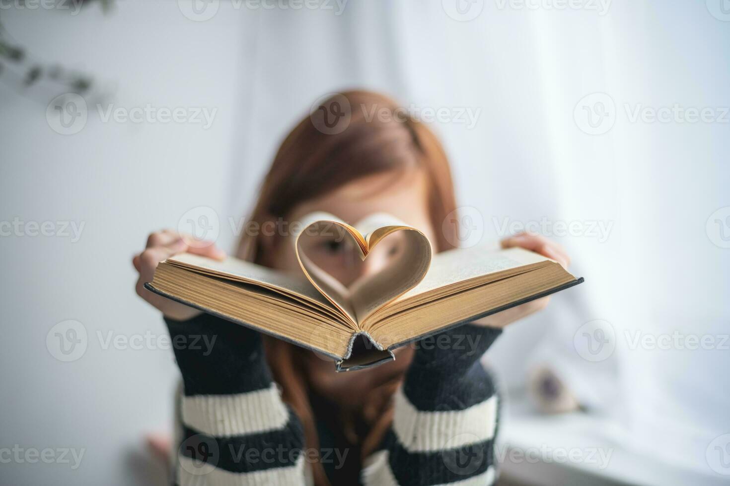 A girl is holding a book. Heart-shaped pages. Reading, Knowing, Learning photo