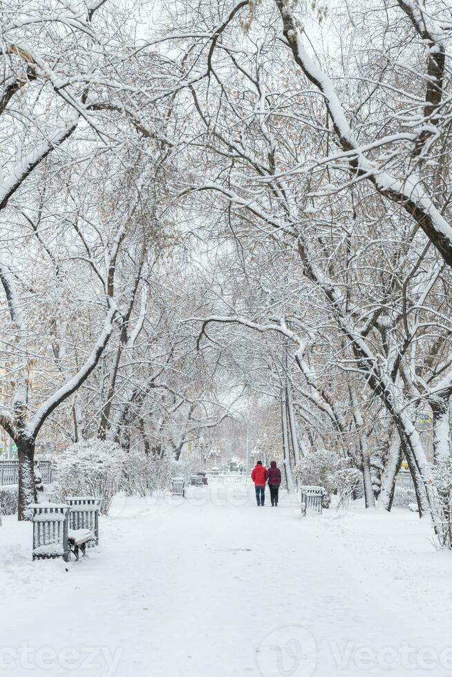 snow-covered city. a man and a woman walk along a snowy alley photo