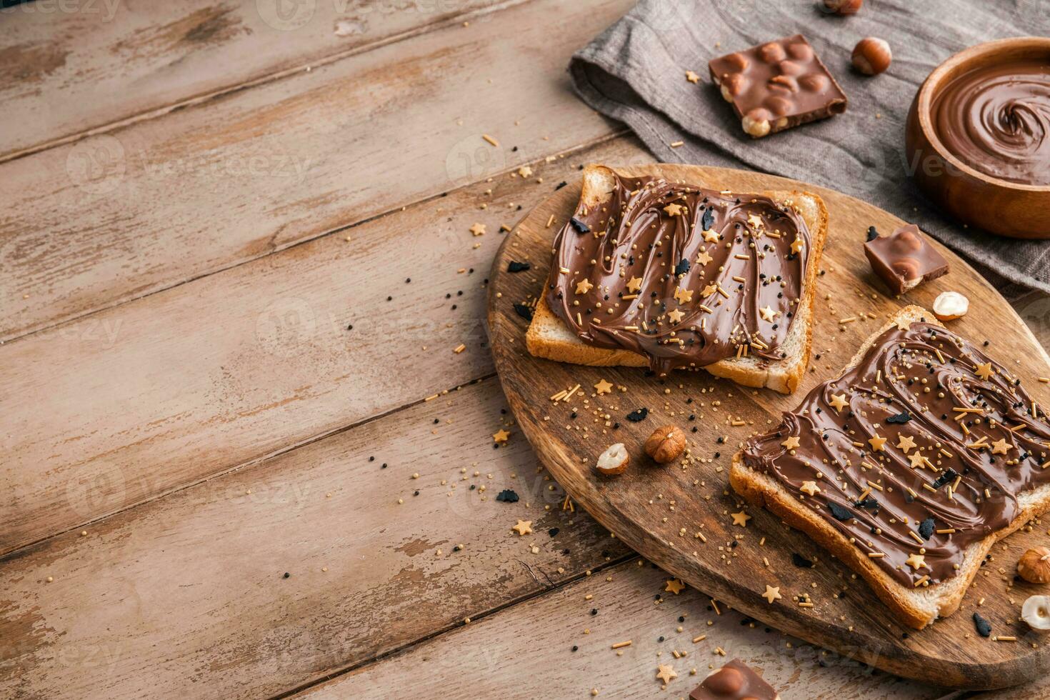 Board of bread with chocolate paste and hazelnuts on wooden background photo