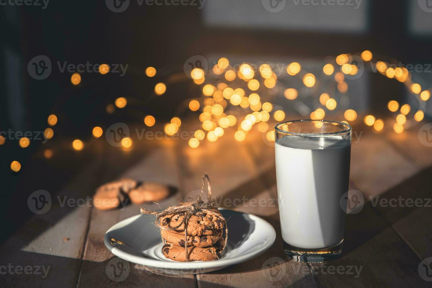 A stack of cookies and glass of milk for Santa on wooden background photo