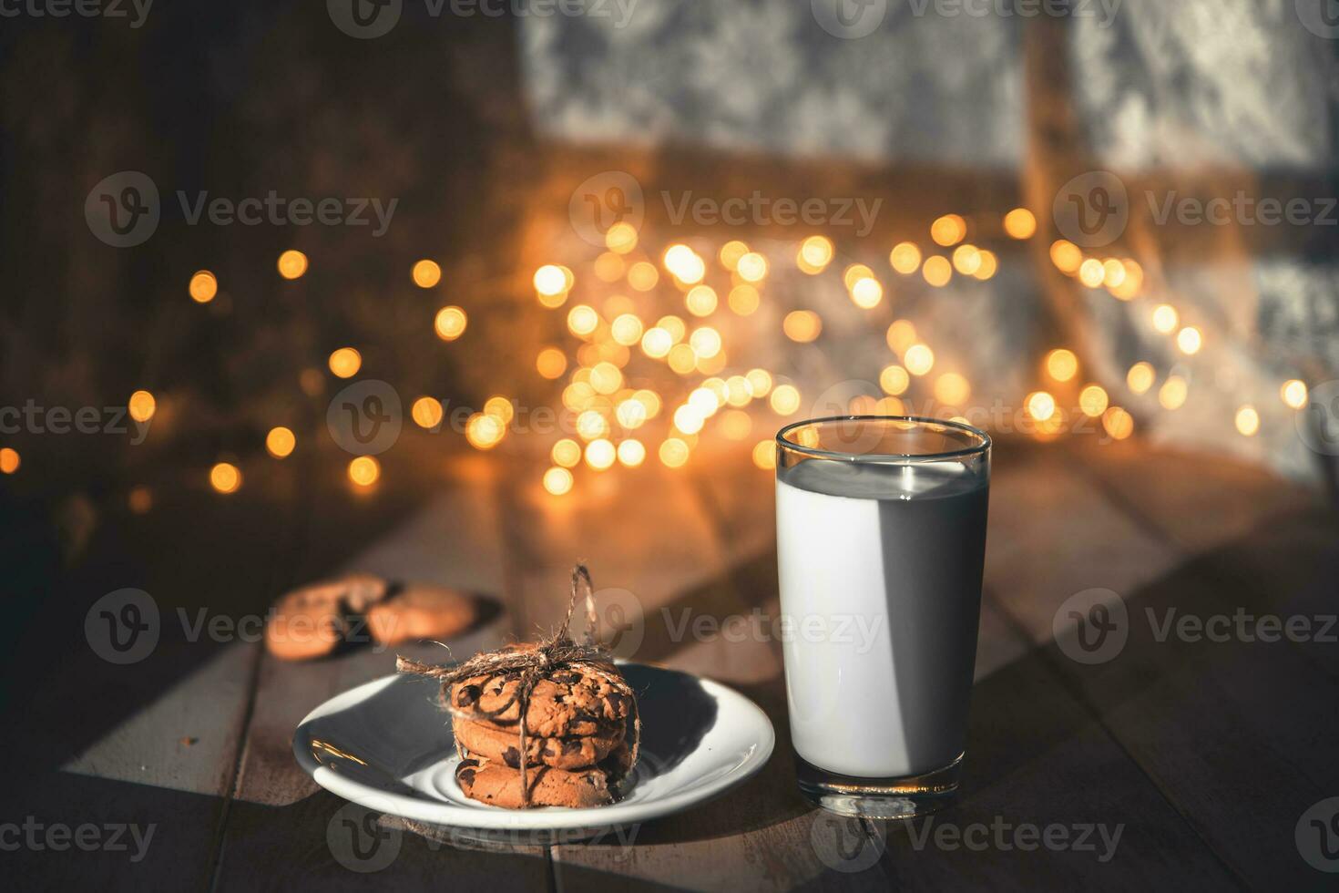 A stack of cookies and glass of milk for Santa on wooden background photo