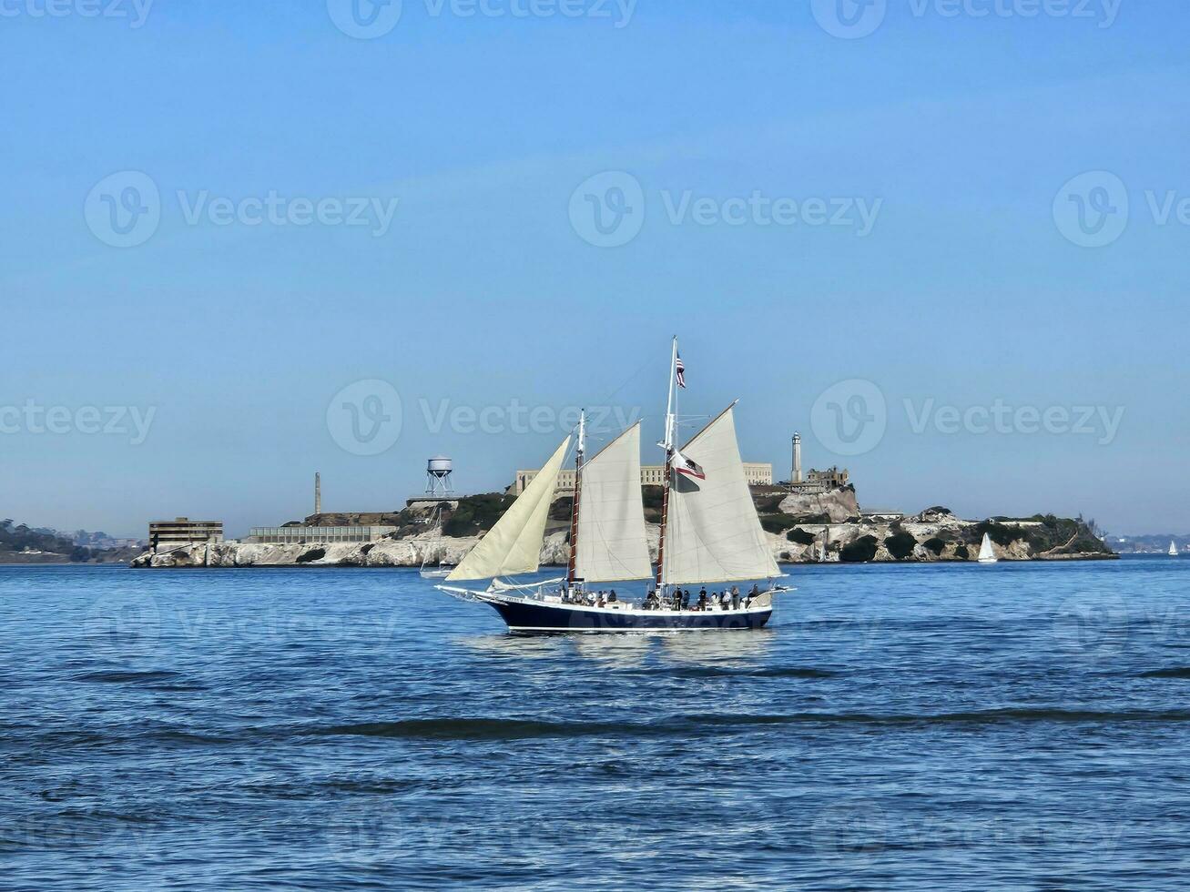 A sail boat crossing in front of Alcatraz Island in San Francisco California photo