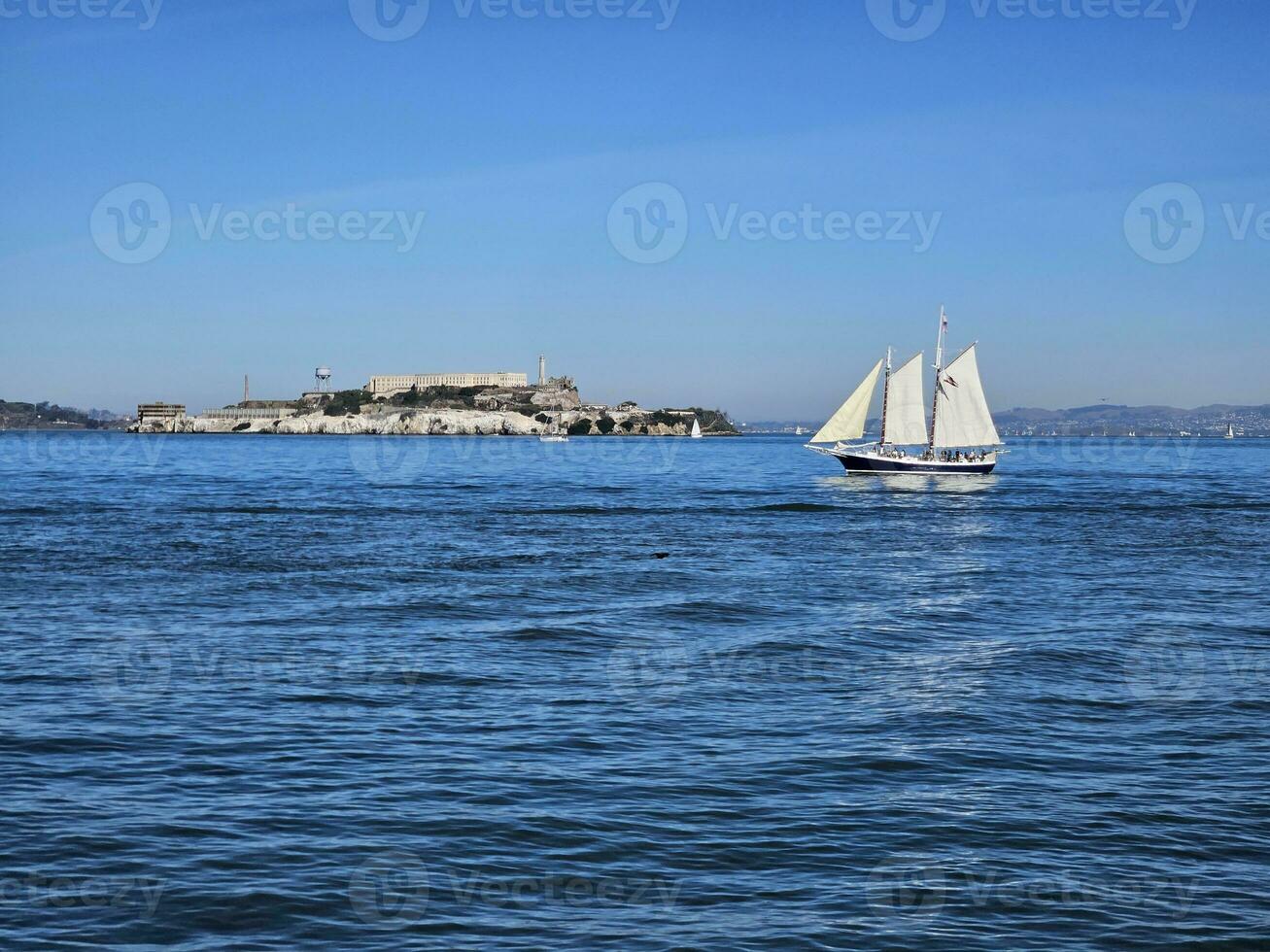 A sail boat crossing in front of Alcatraz Island in San Francisco California photo