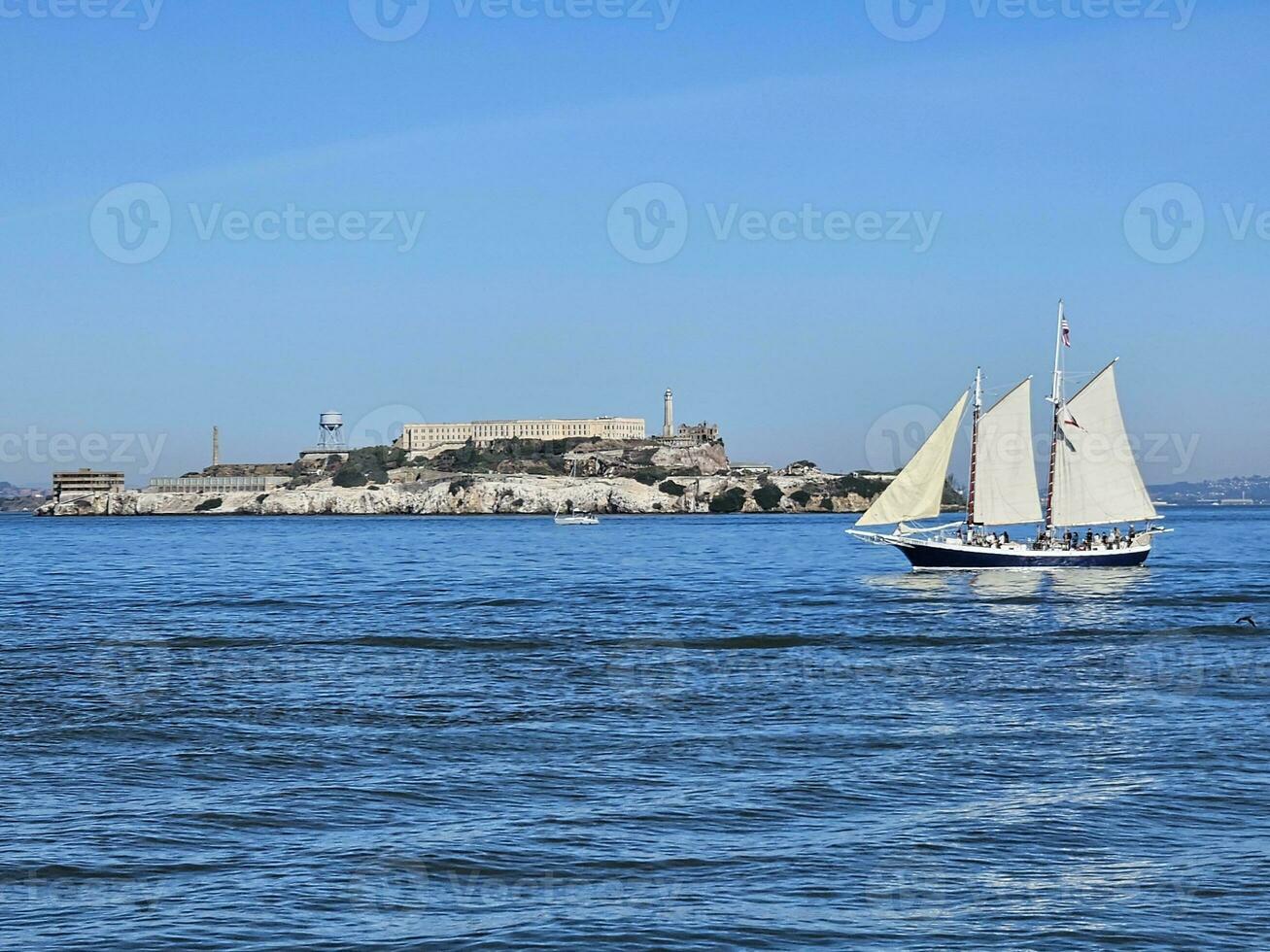 A sail boat crossing in front of Alcatraz Island in San Francisco California photo