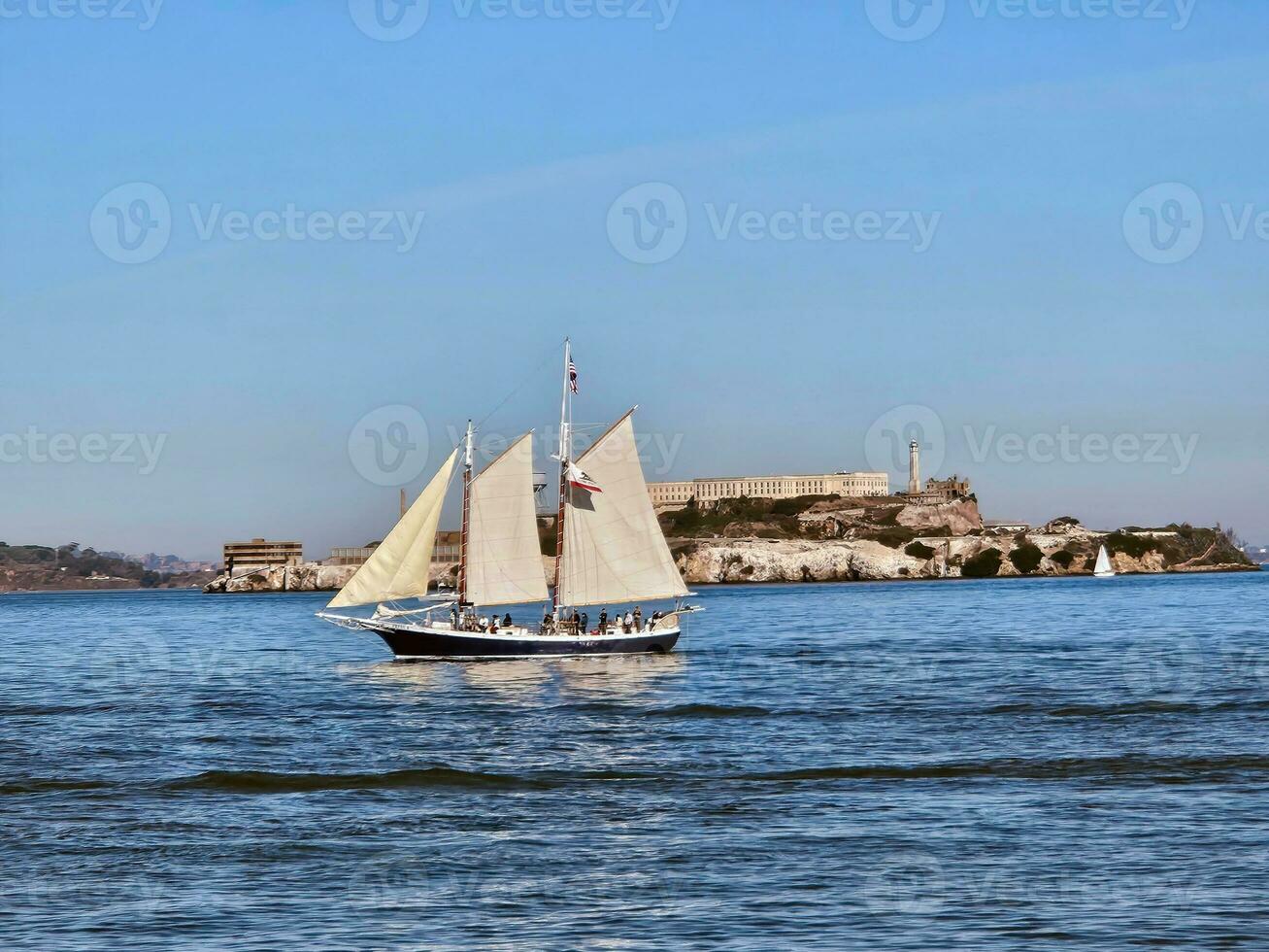 A sail boat crossing in front of Alcatraz Island in San Francisco California photo