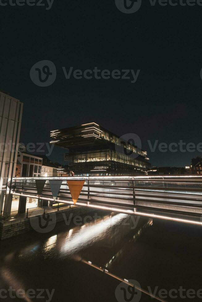 Modern City library De Krook building lit up with yellow and white lights during midnight in the centre of Ghent, Belgium. Flanders region photo