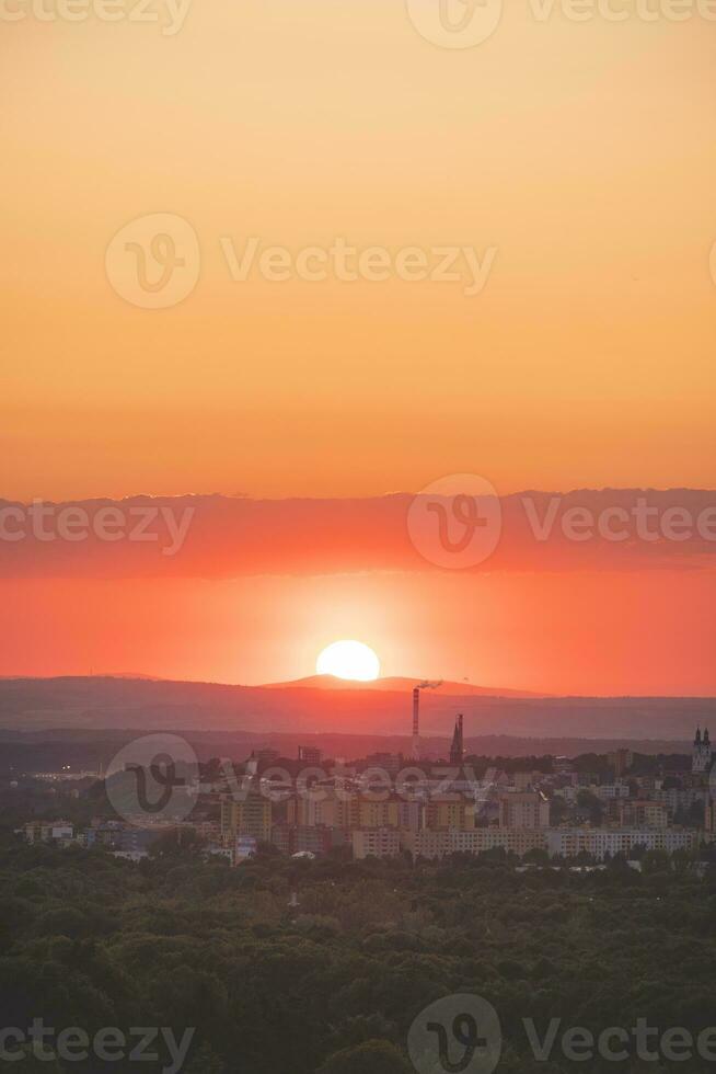 Disc of sunset with reddish hues sets behind the mountains in the distance. Blue, orange and golden sky. Airplane flying over in red sun. Abstract sky photo