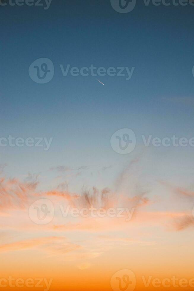 Colourful sky during sunset with reddish hues. Blue, orange and golden sky. Airplane flying over in red sun. Abstract sky photo