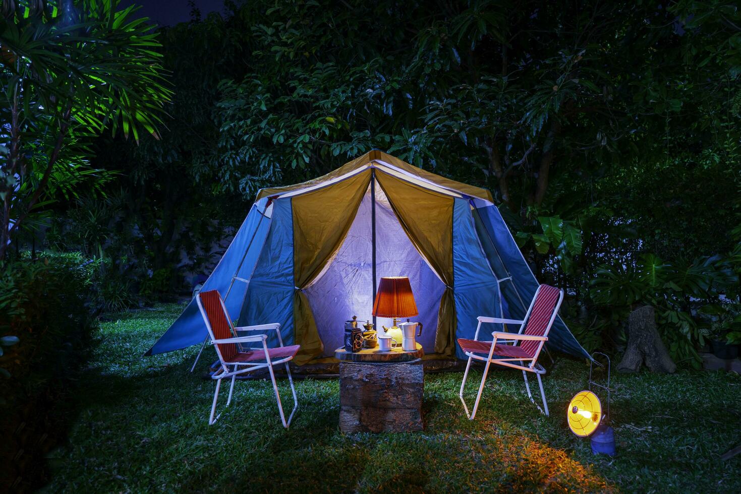 vintage cabin tent,  Antique oil lamp, retro chairs, Group of camping tents with outdoor coffee-making facilities on wooden tables in a forest camping area in the forest. photo