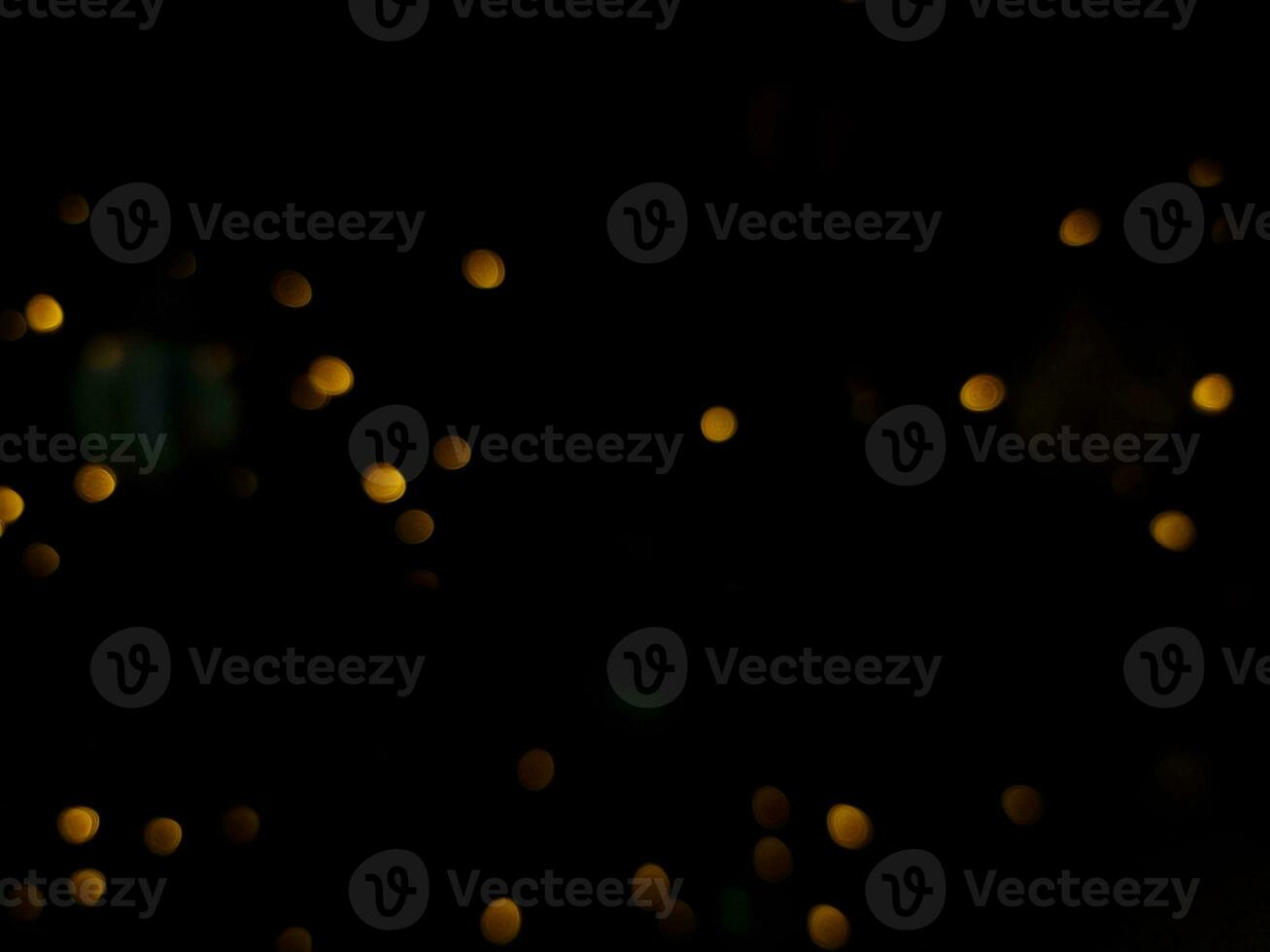 abstract bokeh light orange and yellow glowing flare pattern black background in festival christmas photo