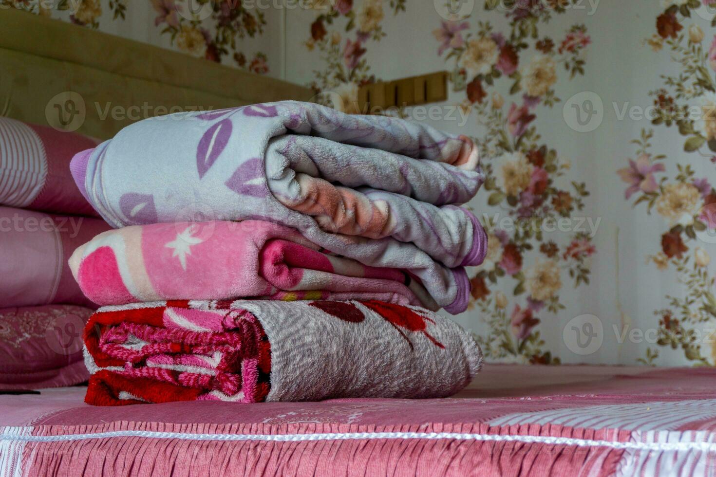 Stacked of colorful blanket on pink bed. Folded pink blankets. White folded duvet lying photo