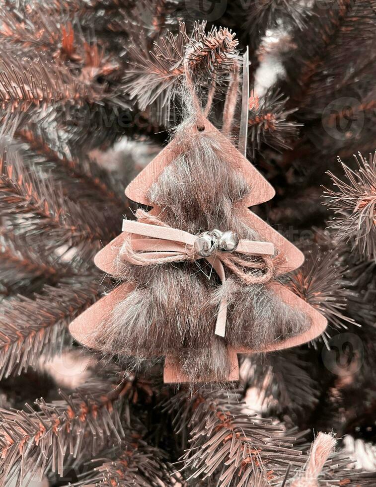 Zero waste. Eco Christmas tree decor toy - wooden pendant is decorated with fur, ribbon and bell, without plastic. Color Of The Year 2024 - Peach Fuzz. photo