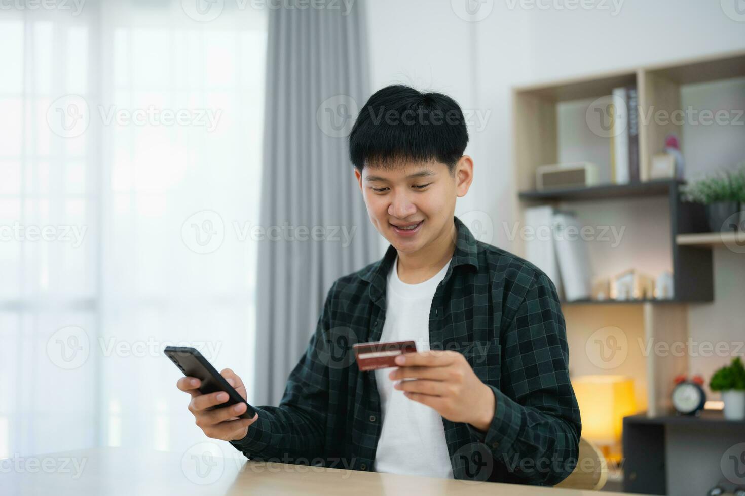 Man holding credit card and using mobile to shopping online. asian man working at home. Online shopping, e-commerce, internet banking, spending money, working from home concept. photo