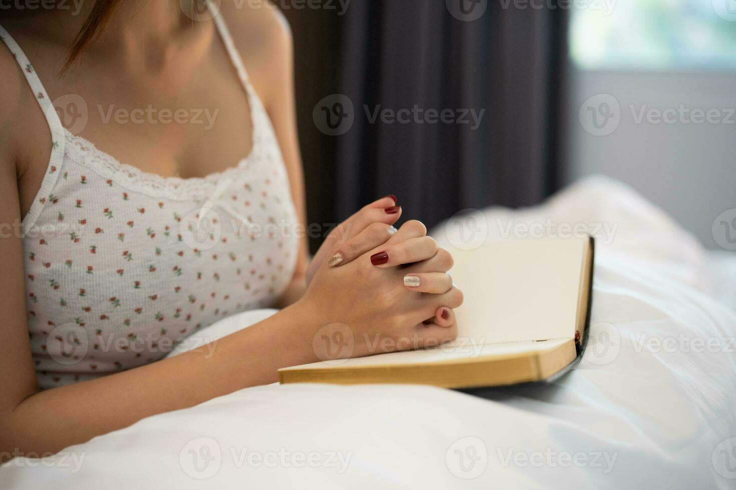 asiático mujer haciendo manos juntos en oración a Dios a lo largo con el Biblia en el cristiano concepto de fe, espiritualidad y religión, mujer orar en el Biblia. oración Biblia en el cama en el dormitorio. foto