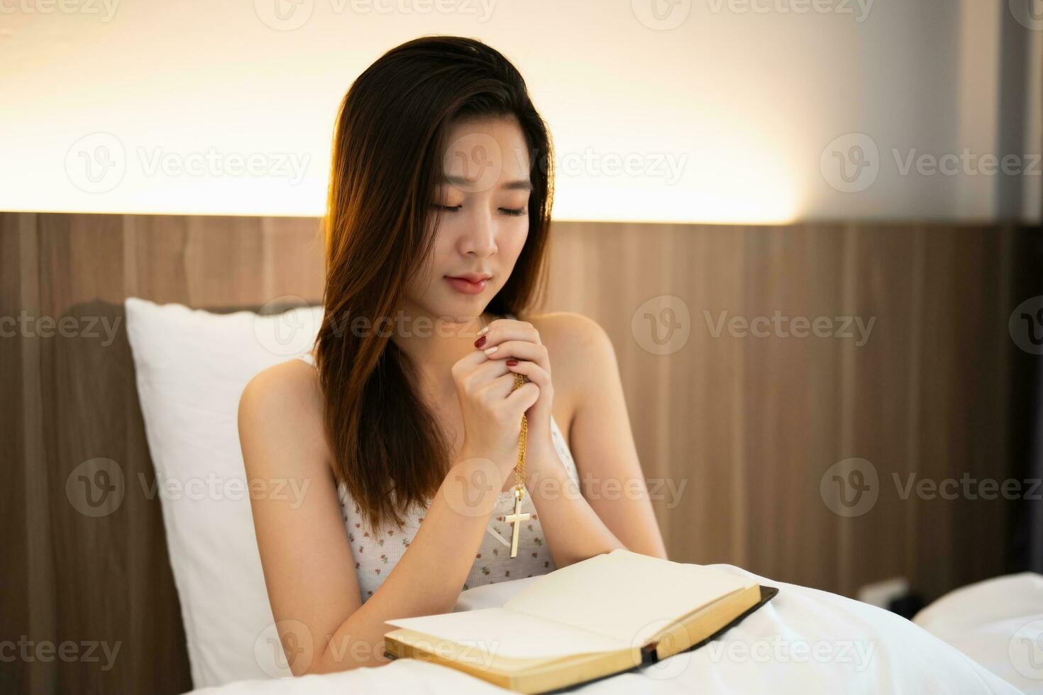 asiático mujer haciendo manos juntos participación cruzar en oración a Dios a lo largo con el Biblia cristiano concepto de fe, espiritualidad y religión, orar en el Biblia. oración Biblia en el cama en el dormitorio. foto