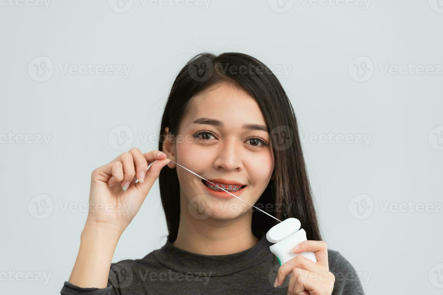 asiático mujer tirantes utilizando dental seda floja. dientes tirantes en el blanco dientes de mujer a igualar el dientes. soporte sistema en sonriente boca, cerca arriba foto dientes, macro disparo, dentista salud concepto.