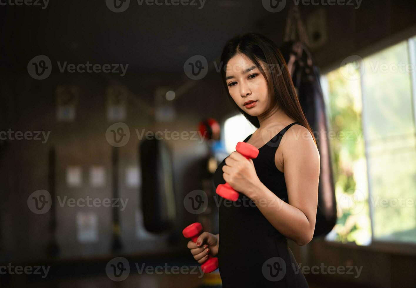 Asian fit sportswoman smiling and working out excercise weights with dumbbells at the fitness gym. asian woman wearing sportwear doing exercise to burn fat at gym. Sport woman fitness concept. photo