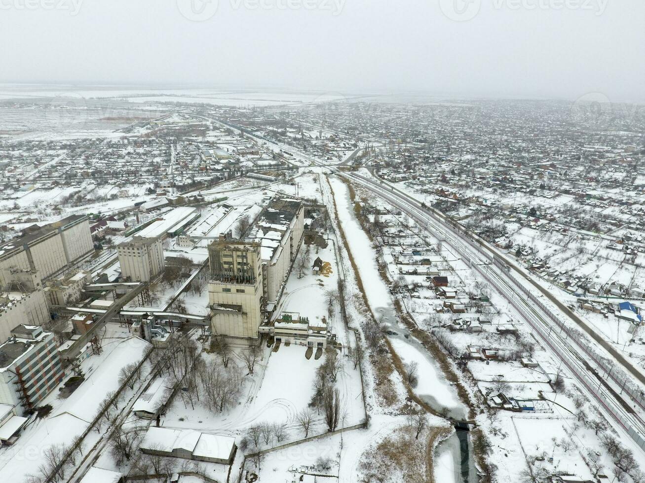 Sprinkled with snow grain elevator. Winter view of the old Soviet elevator. Winter view from the bird's eye view of the village. The streets are covered with snow photo