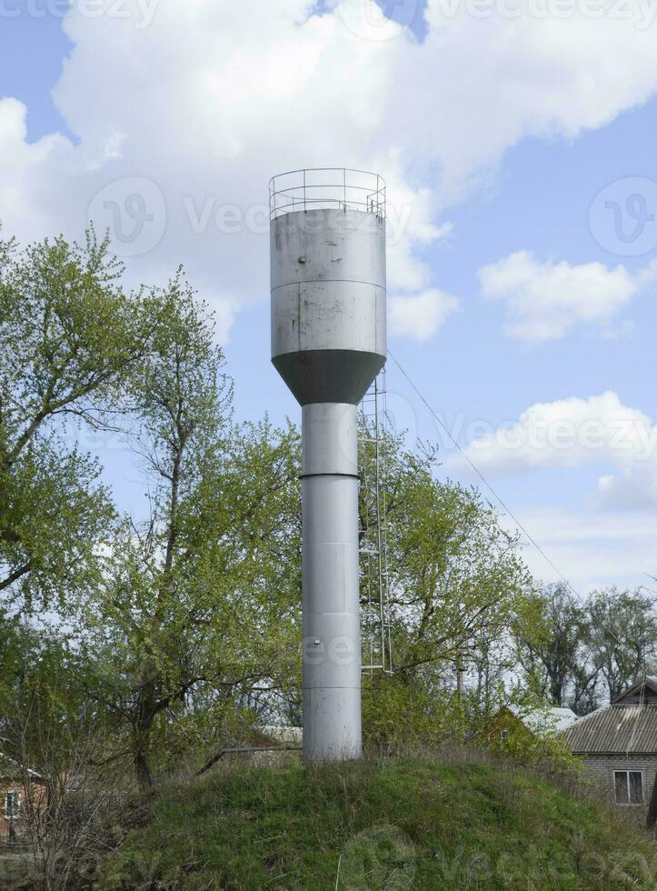 Silver Water Tower among green grass and trees photo