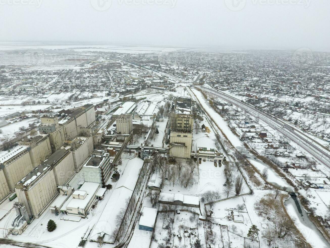 Sprinkled with snow grain elevator. Winter view of the old Soviet elevator. Winter view from the bird's eye view of the village. The streets are covered with snow photo