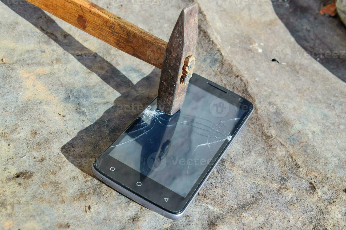 Hammer and smartphone. The screen of the smartphone, a broken ha photo