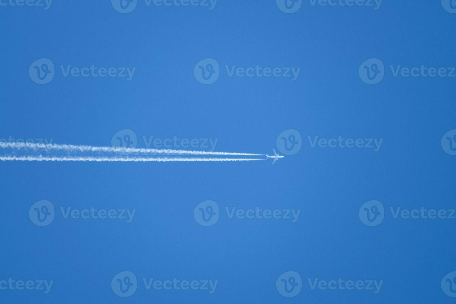 Condensation trail from an airplane in a blue sky photo