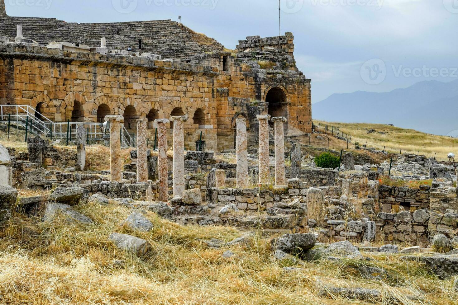 Ancient antique amphitheater in city of Hierapolis in Turkey. Side view. Steps and antique statues with columns in the amphitheater photo