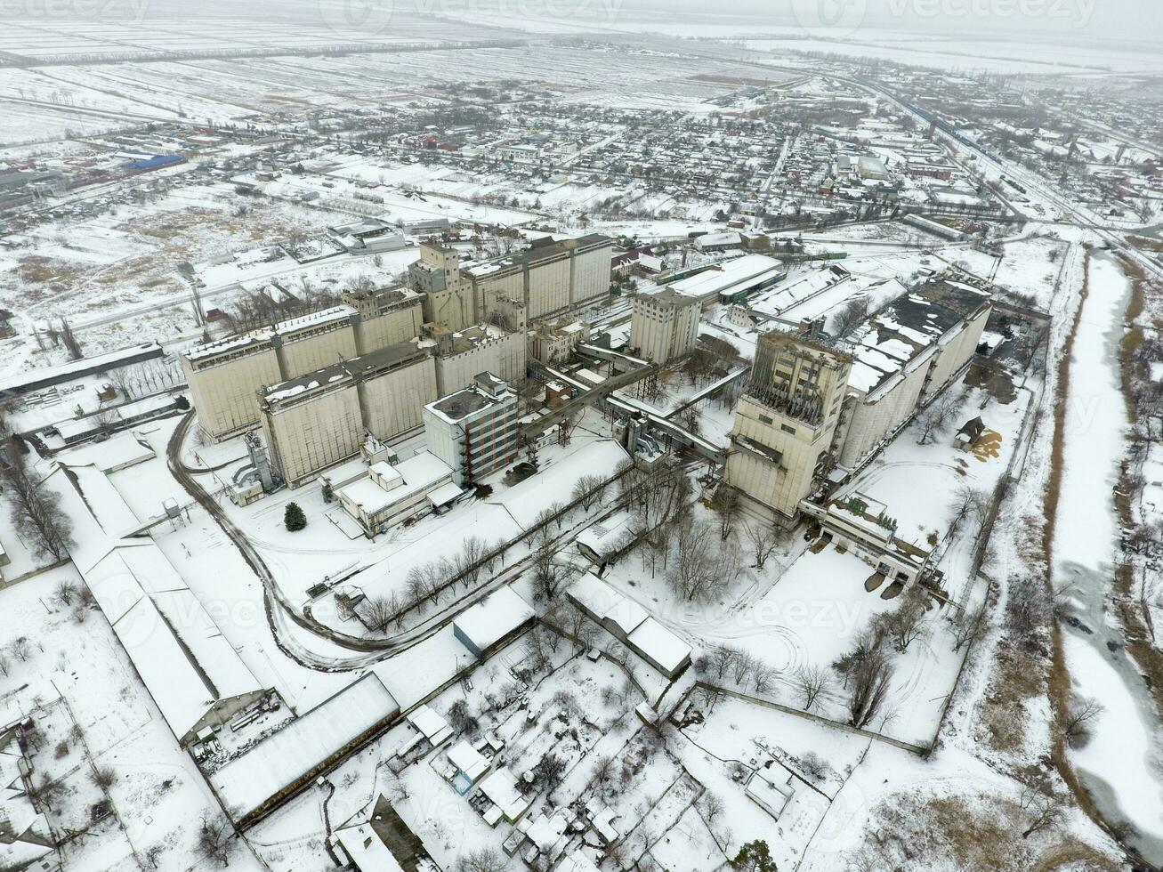 Sprinkled with snow grain elevator. Winter view of the old Soviet elevator. Winter view from the bird's eye view of the village. The streets are covered with snow photo