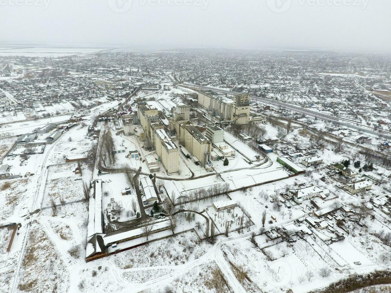 Sprinkled with snow grain elevator. Winter view of the old Soviet elevator. Winter view from the bird's eye view of the village. The streets are covered with snow photo