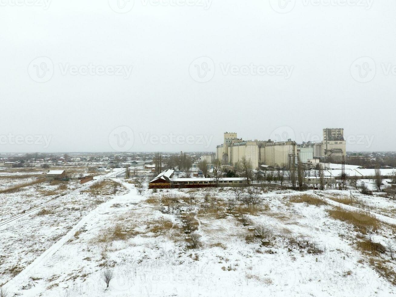 Sprinkled with snow grain elevator. Winter view of the old Soviet elevator. Winter view from the bird's eye view of the village. The streets are covered with snow photo