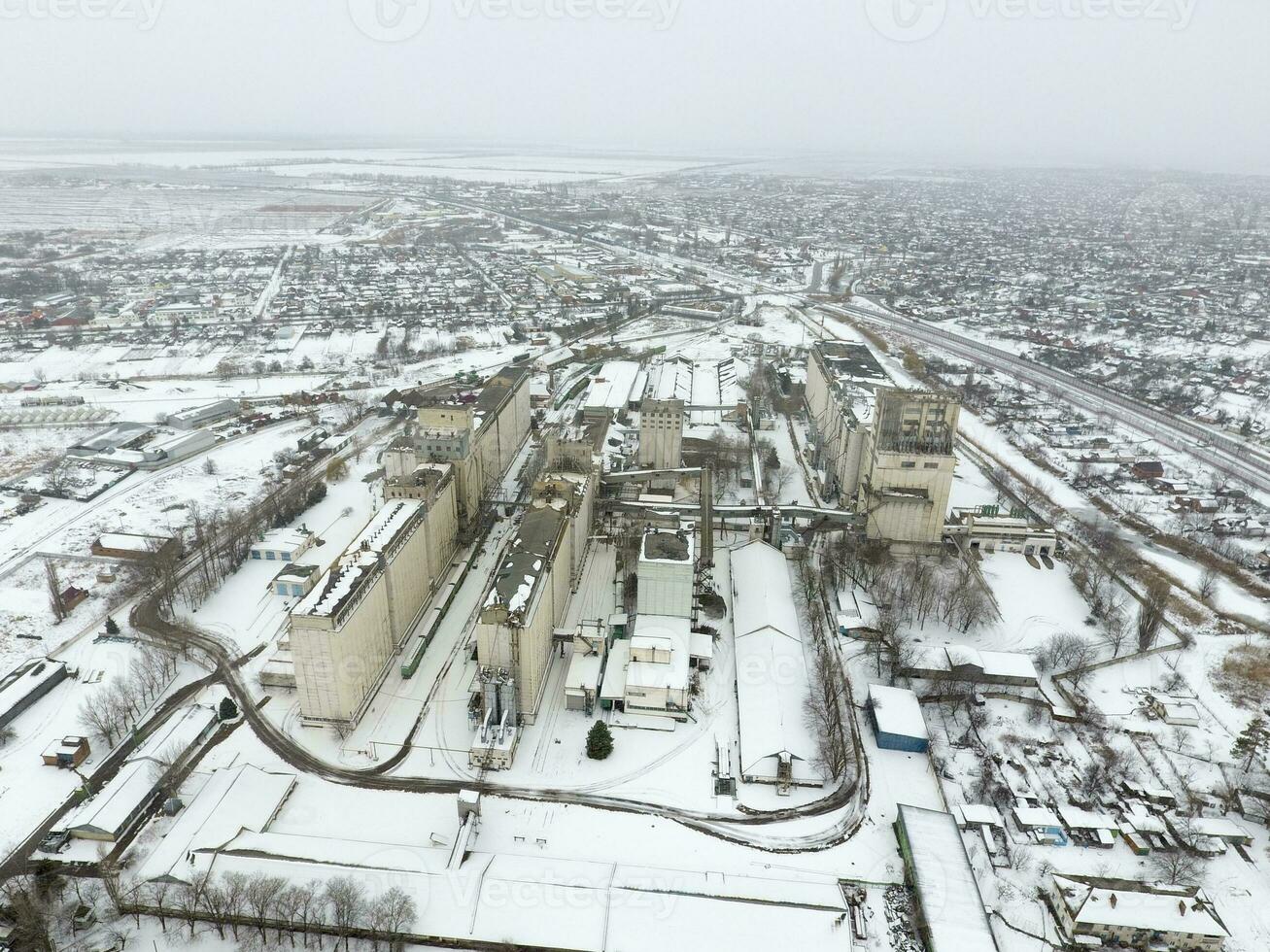 Sprinkled with snow grain elevator. Winter view of the old Soviet elevator. Winter view from the bird's eye view of the village. The streets are covered with snow photo