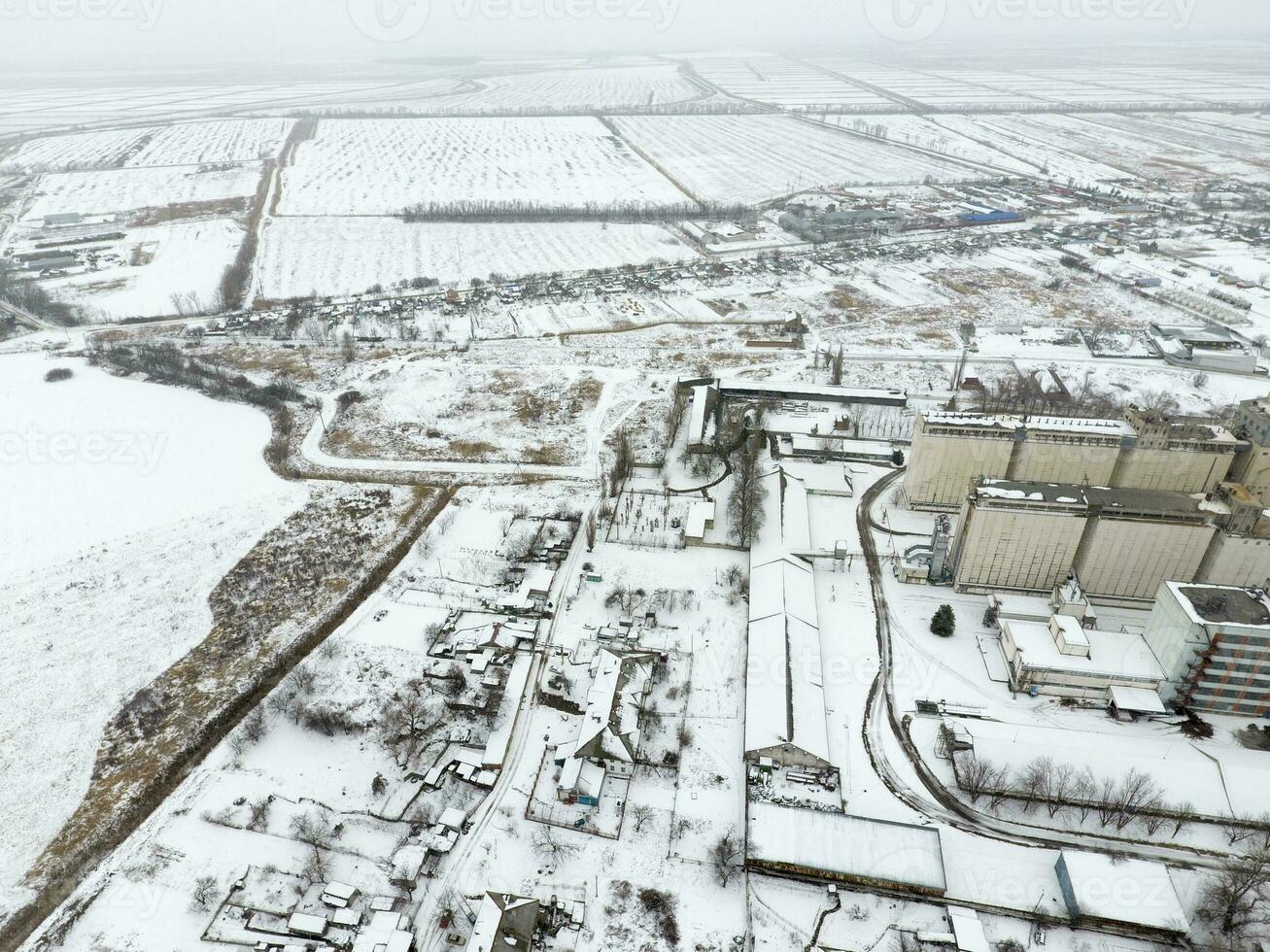 Sprinkled with snow grain elevator. Winter view of the old Soviet elevator. Winter view from the bird's eye view of the village. The streets are covered with snow photo