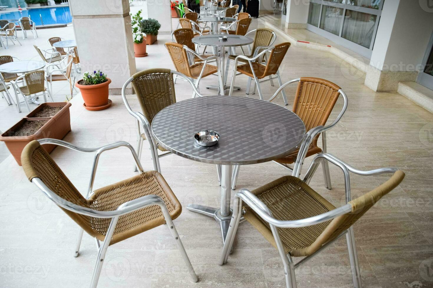 Metal tables and chairs with wicker seats in outdoor cafe. photo