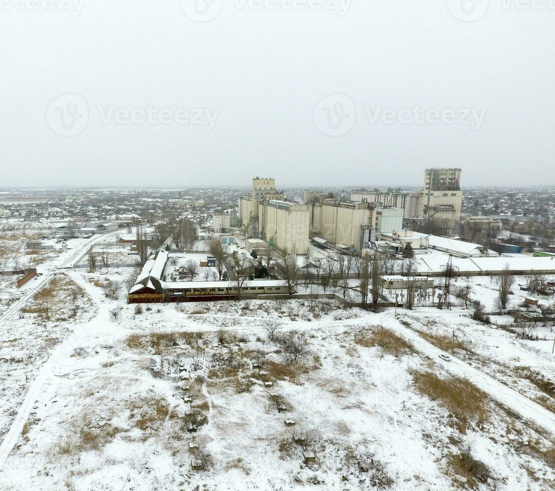 Sprinkled with snow grain elevator. Winter view of the old Soviet elevator. Winter view from the bird's eye view of the village. The streets are covered with snow photo