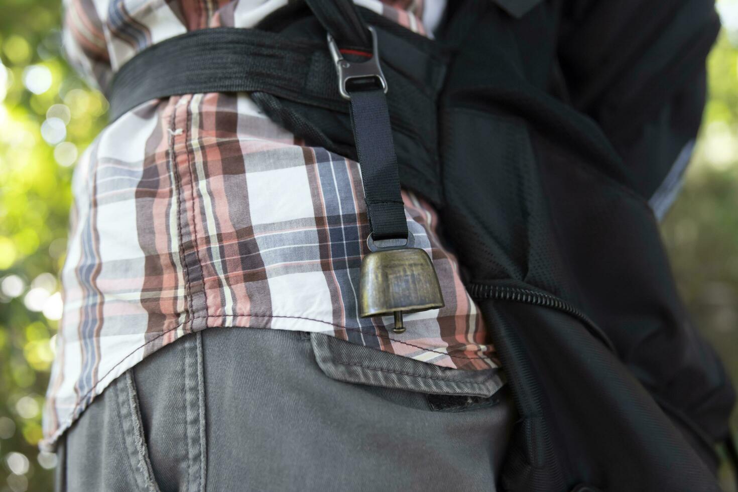 A person who wear a backpack with bear bell at the green forest in Autumn photo