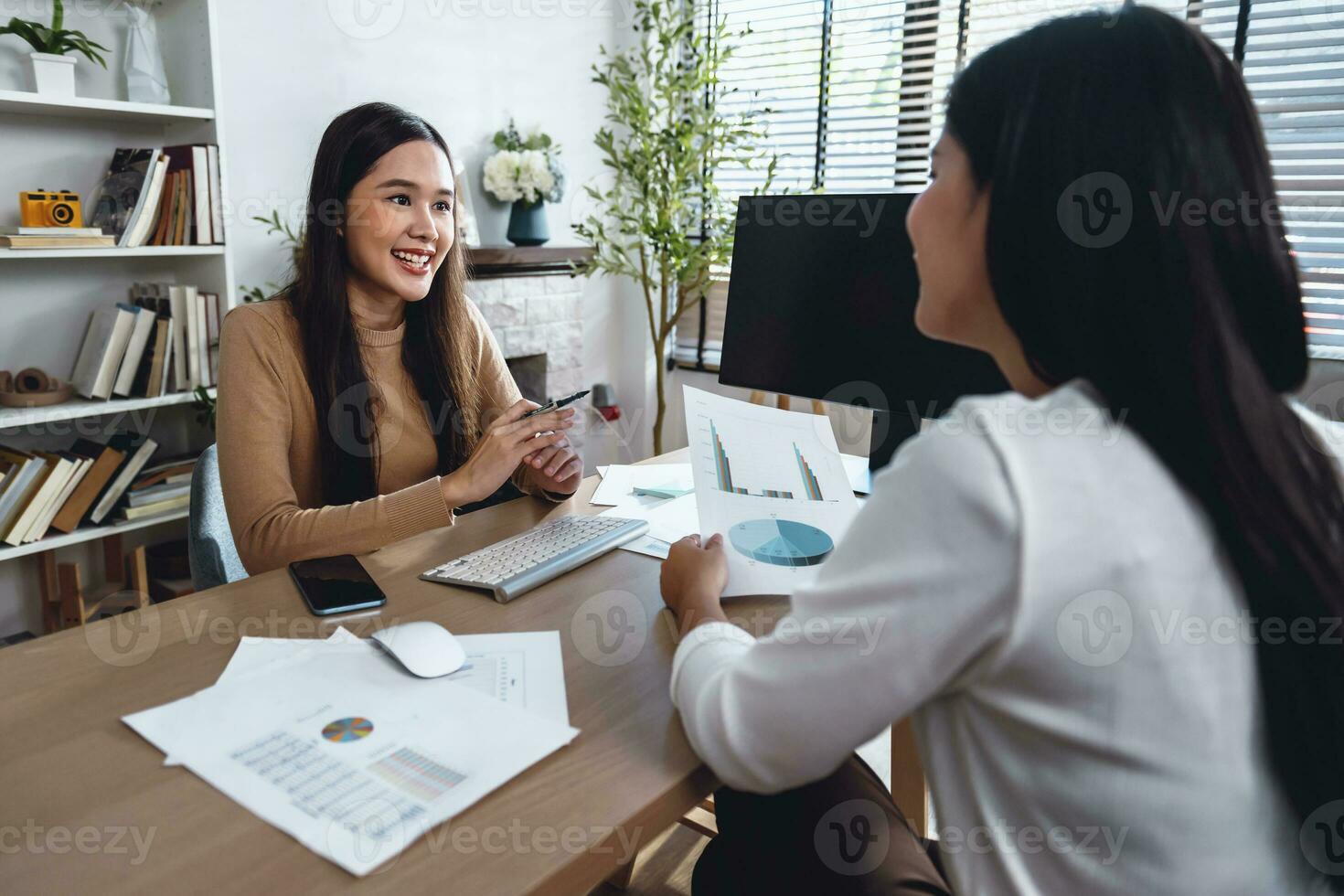 Two female accountants have a team meeting to summarize financial information in the office photo
