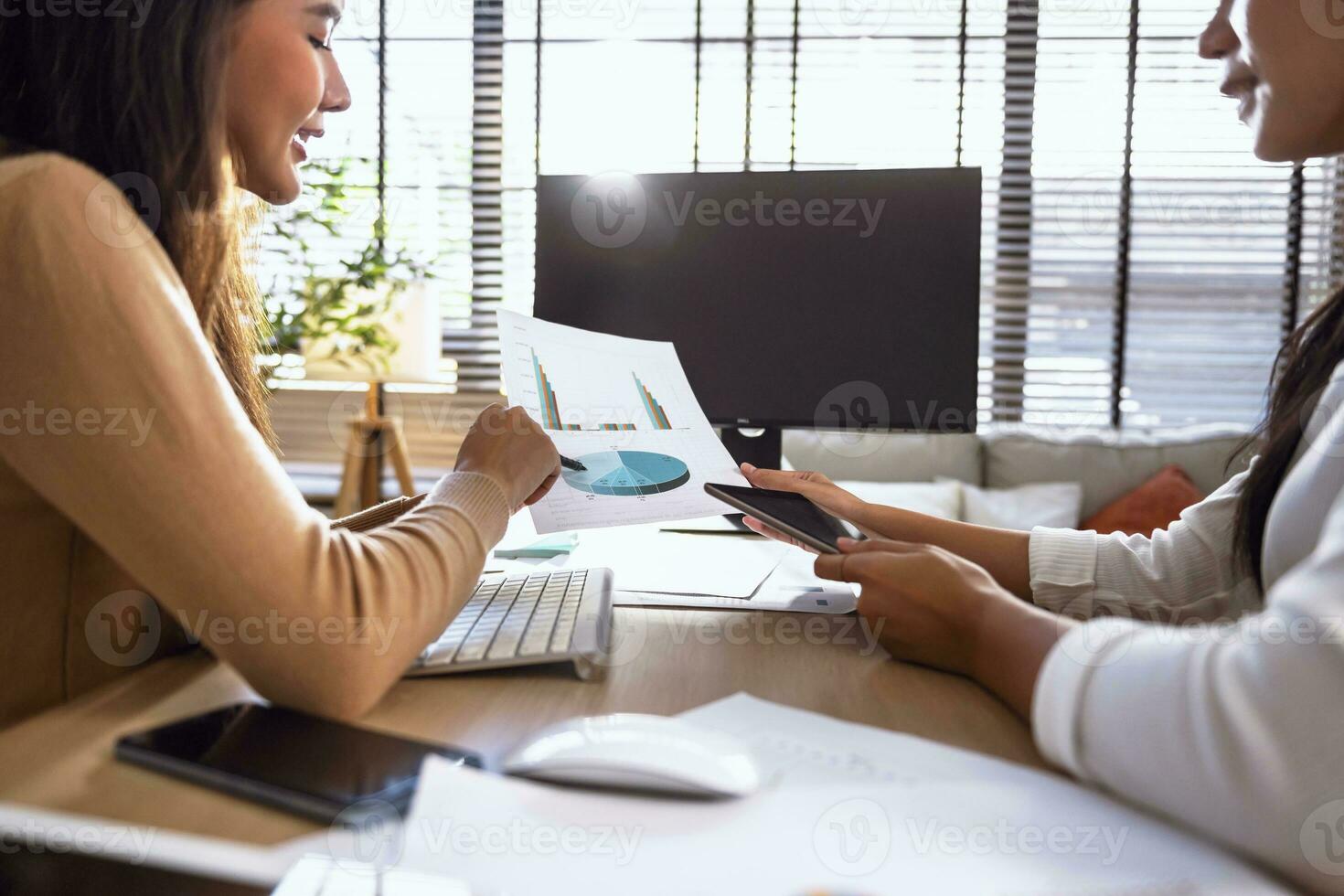 Two female accountants have a team meeting to summarize financial information in the office photo
