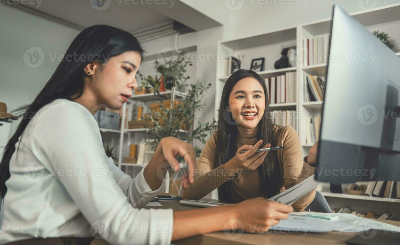 Two female accountants have a team meeting to summarize financial information in the office photo