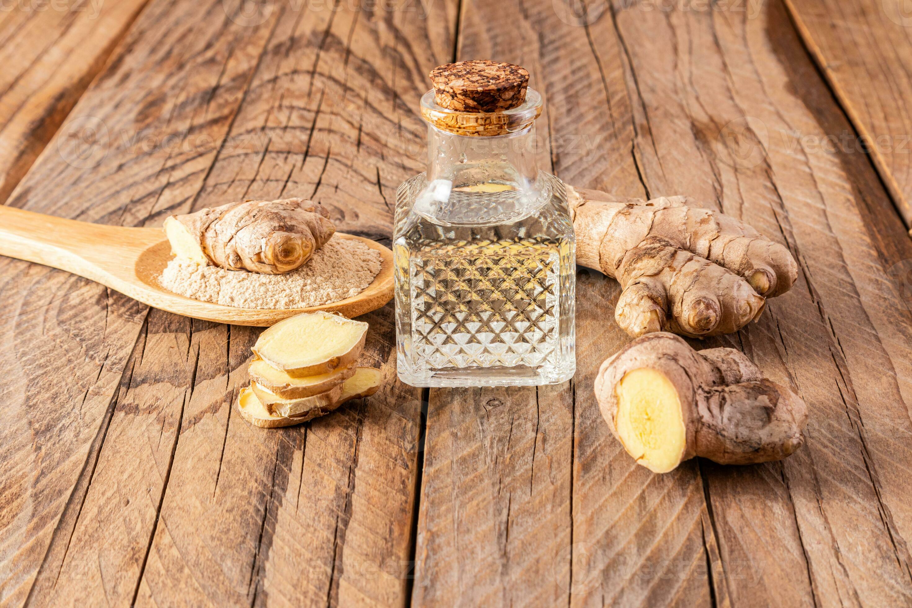 Homemade natural ginger root oil in bottle with a cork cap on a wooden
