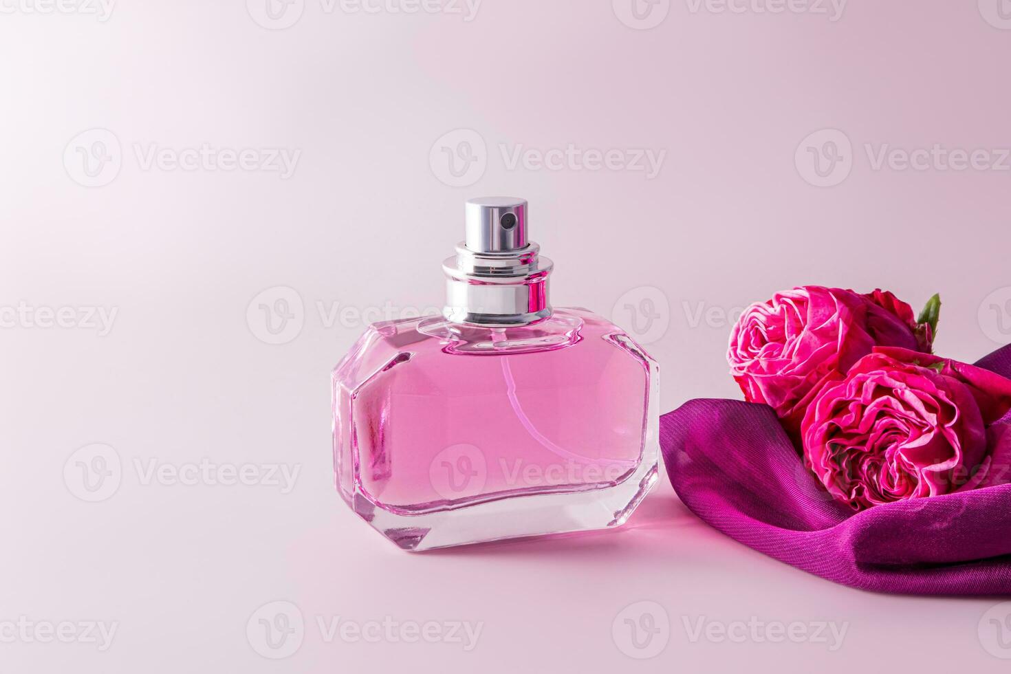 Beautiful bottle of women's perfume on pastel background with roses . Presentation of the delicate fragrance of perfume. A copy space. layout. photo