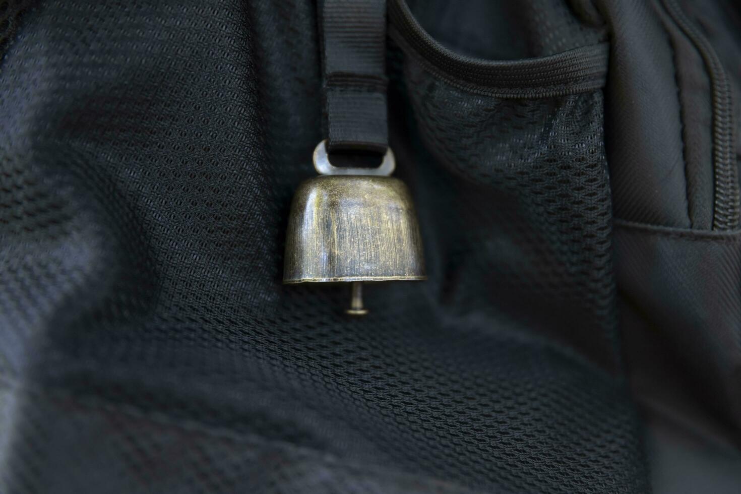 A backpack with bear bell at the green forest in Autumn closeup photo