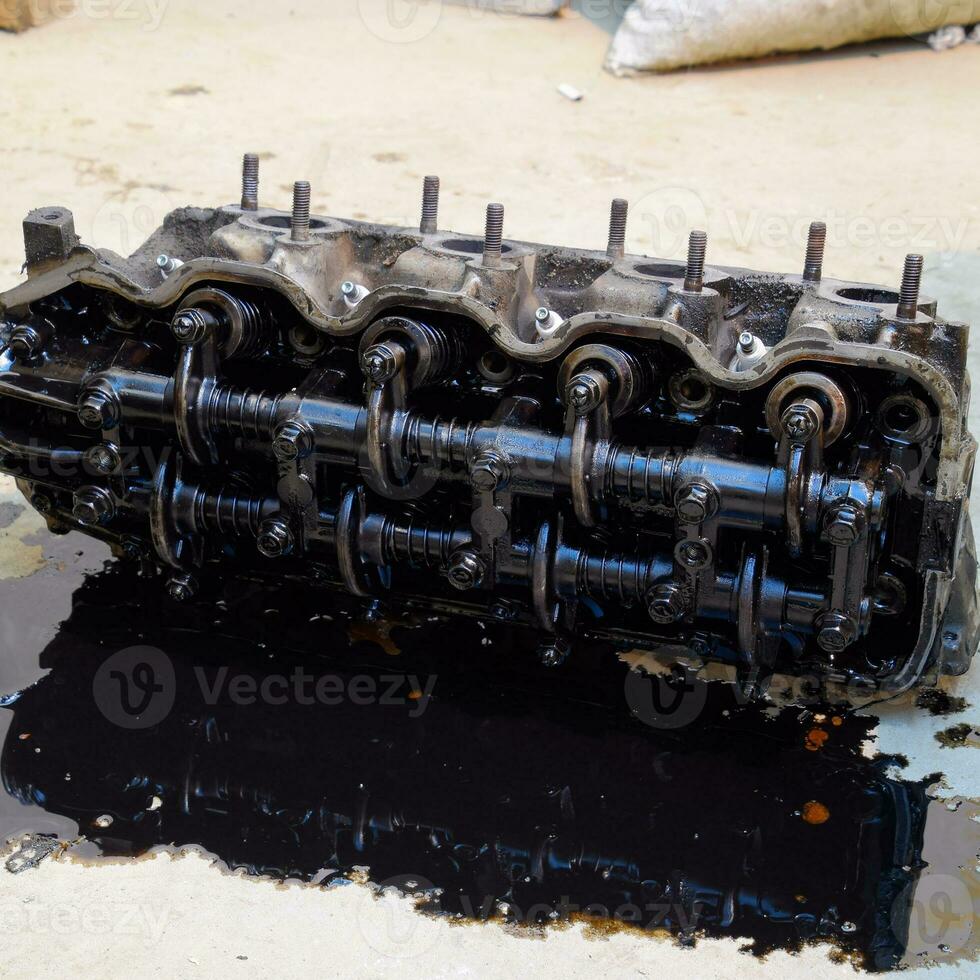 The head of the block of cylinders. The head of the block of cylinders removed from the engine for repair. Parts in engine oil. Car engine repair in the service photo